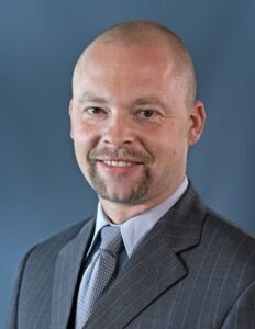 A bald man wearing a suit and tie.